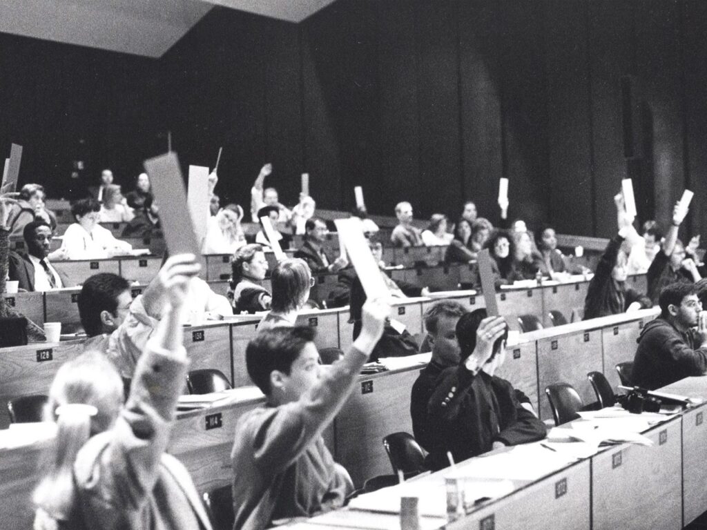 Une assemblée étudiante de l'AGEFAC dans les années 1980, mains levées pour voter