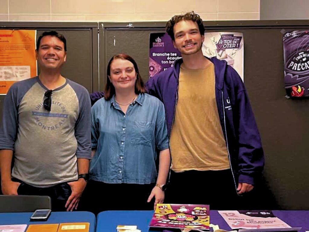 Trois membres de l'équipe AGEFAC, souriants, à un kiosque d'information